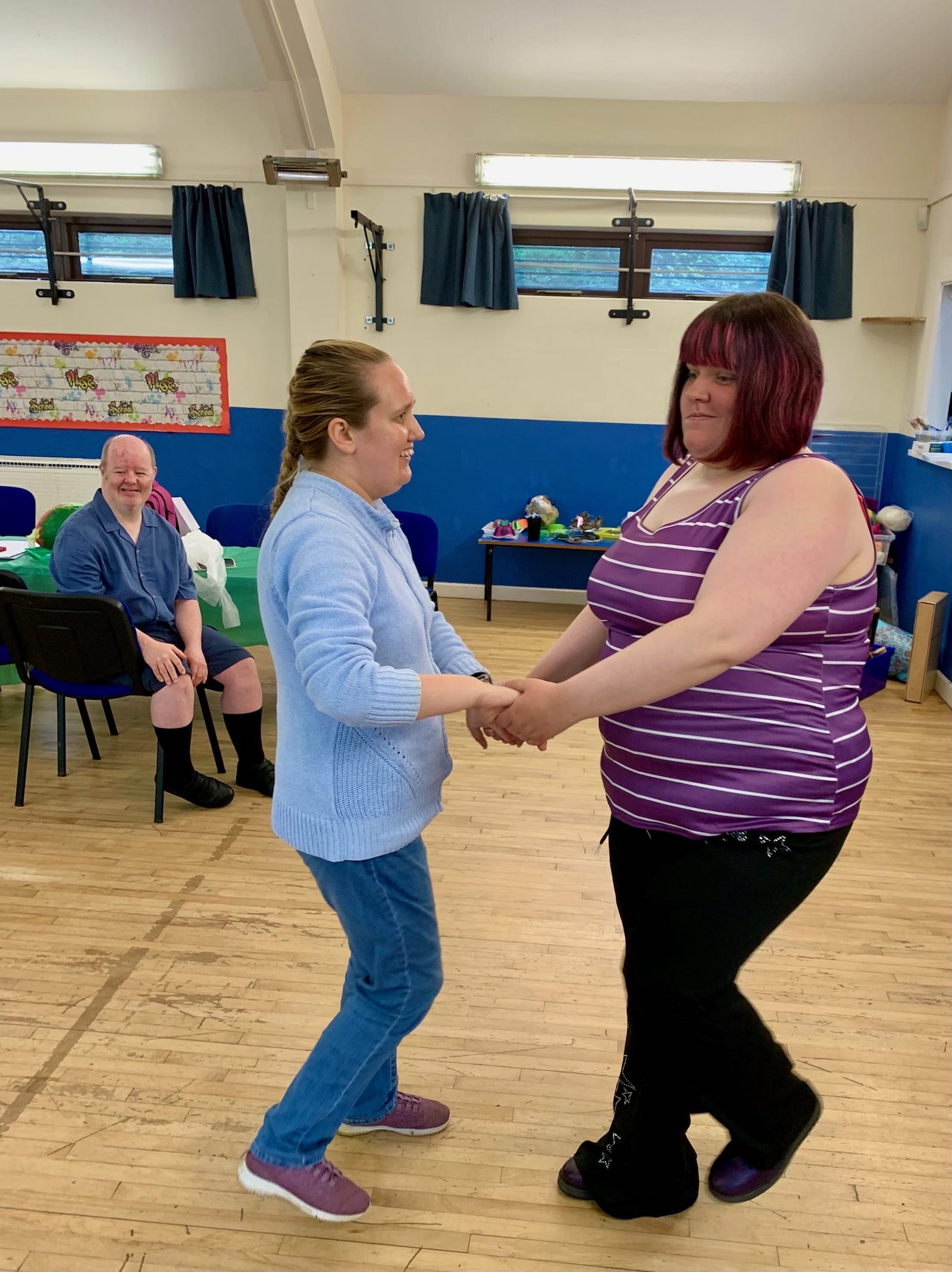 Two people holding hands and dancing together in the community center