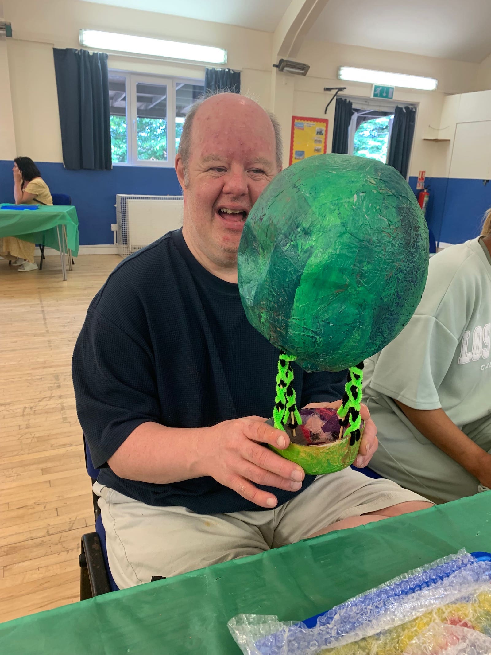 Participant beaming with joy holding large green spherical artwork