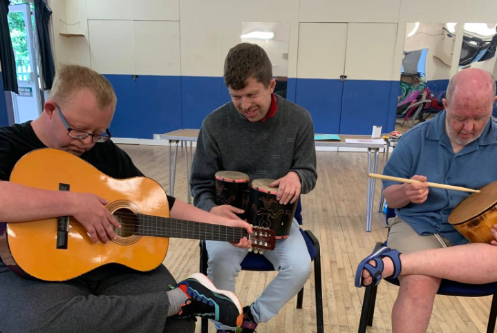 Music therapy session with participants playing guitars