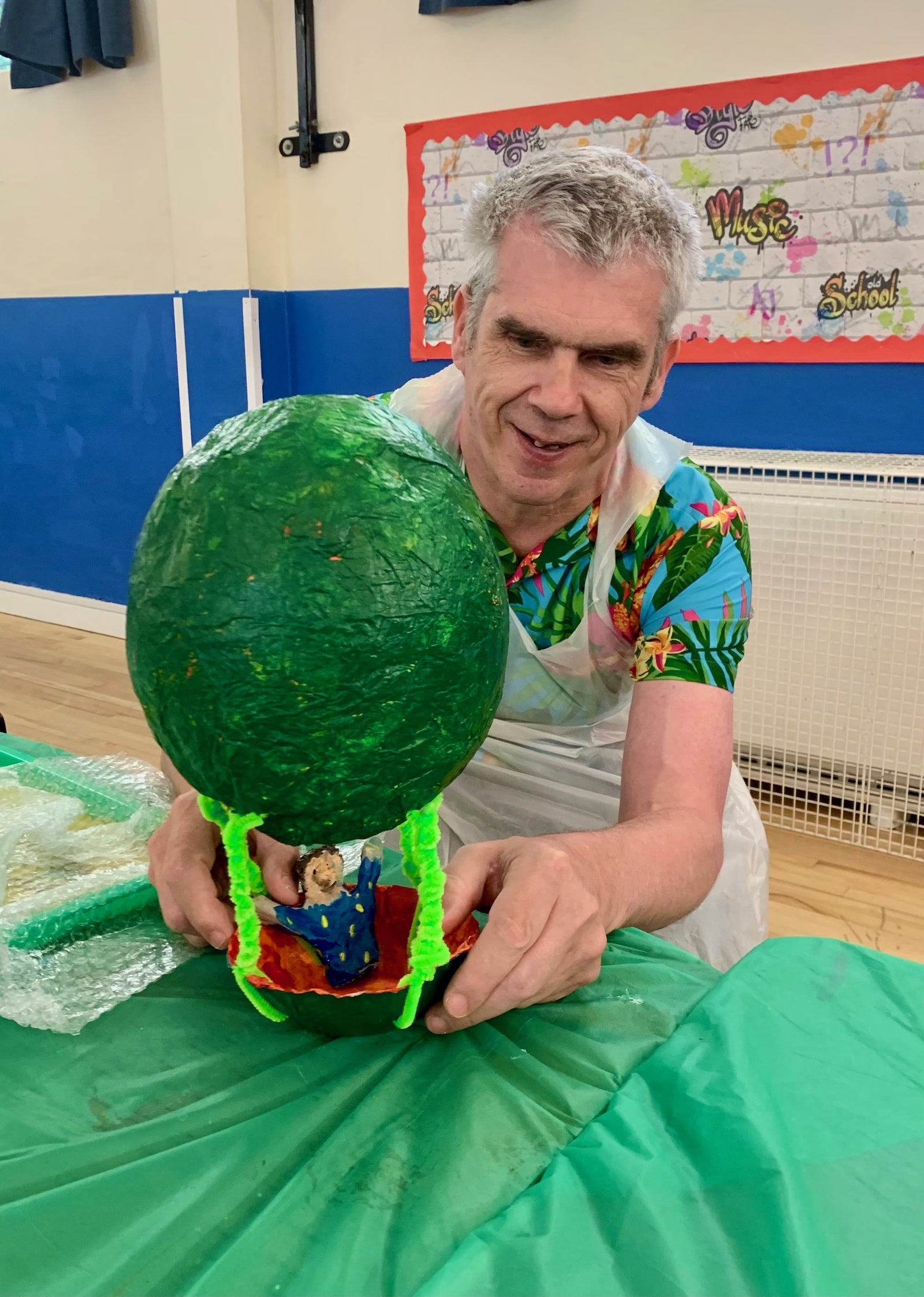 Participant proudly displaying handmade green tree sculpture with colorful base